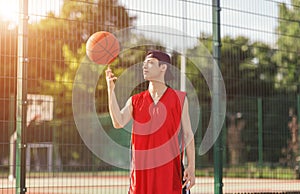 Millennial Asian basketball player with ball on outdoor court