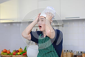 Millennial Asian excited shocked worried frightened stressed male chef wearing white tall cook hat and apron standing open mouth