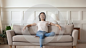 Millennial asian girl relax on modern sofa at home