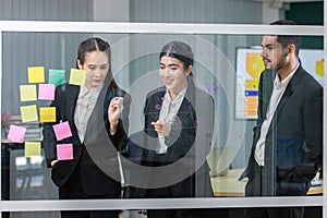 Millennial Asian professional successful female businesswoman in formal business suit standing using marker writing ideas strategy