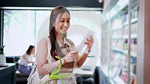 Millennial Asian woman shopping in groceries in supermarket buying food while checking receipt in convenience store