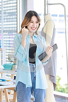 Millennial Asian young excited cheerful surprised professional female dressmaker designer seamstress with measuring tape standing