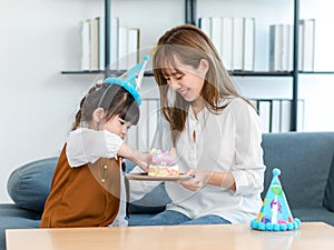 Millennial Asian young female teenager mother nanny babysitter sitting holding dish while little cute preschooler daughter