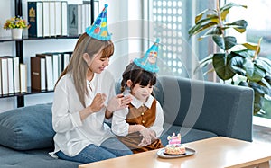 Millennial Asian young female teenager mother nanny babysitter wearing tall hat sitting together with little cute preschooler