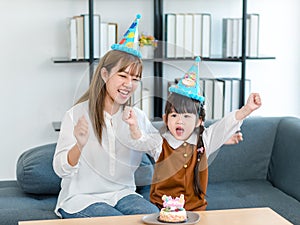 Millennial Asian young female teenager mother nanny babysitter wearing tall hat sitting together with little cute preschooler