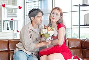 Millennial Asian young handsome male boyfriend reconciling beautiful female sulking upset angry girlfriend in red dress with white