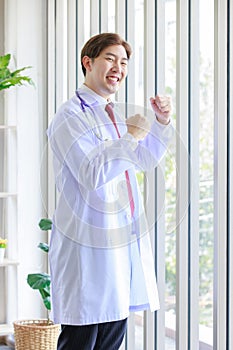 Millennial Asian young handsome professional successful male general doctor in white laboratory coat clinical uniform with