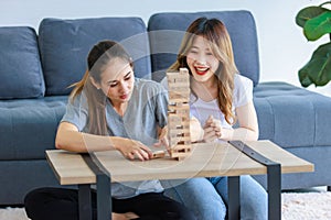 Millennial Asian young happy cheerful joyful female lesbian LGBTQ lover couple sitting smiling laughing together on carpet floor