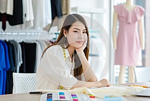 Millennial Asian young professional female designer dressmaker businesswoman with measuring tape fabric textile on working desk