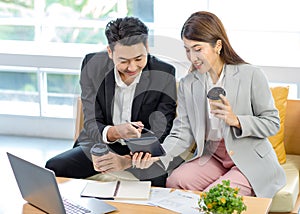 Millennial Asian young professional successful businessman employee in formal suit sitting on sofa smiling typing laptop computer