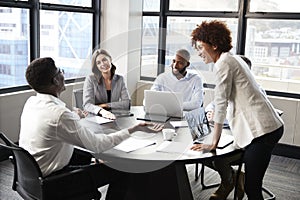 Millennial black businesswoman stands listening to corporate colleagues at a meeting, close up