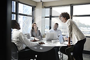 Millennial black businesswoman stands listening to corporate colleagues at a meeting, close up