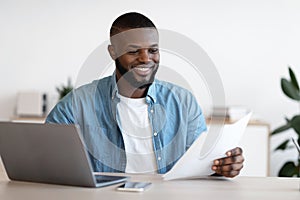 Millennial Black Freelancer Man Working With Papers At Desk In Home Office