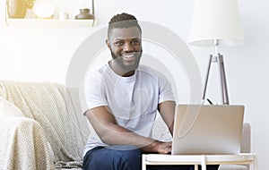 Millennial black man working on laptop in home office photo