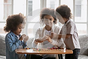 Millennial Black mom teaching kids to make craft decoration