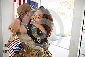 Millennial African American  soldier embracing his wife after arriving back home,close up
