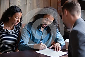 Millennial black spouses signing formal paper in presence of lawyer