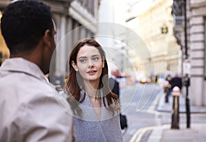 Millennial business colleagues standing on a street in London having a conversation, close up