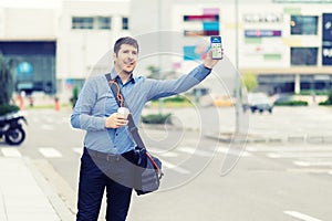 Millennial business man with hand up calling taxi or ride share car hailing from sidewalk photo