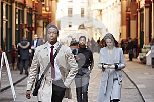 Millennial business people walking in a London street, front view