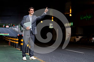 Millennial businessman catching car taxi on the street