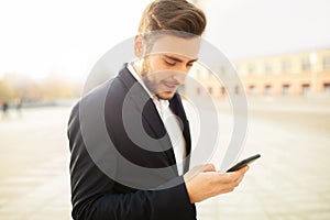 Millennial businessman looks into the screen of his mobile phone.