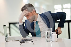 Millennial Businessman in office having headache. Business man in suit work on laptop at home office take off glasses