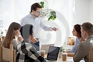 Millennial businessman stand leading meeting scolding colleague