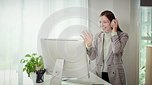 Millennial businesswoman wearing headphone talking on video call working in her home office