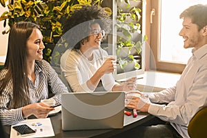 Millennial colleagues enjoying coffee and discussing work in cafe