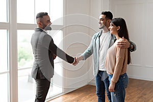 Millennial Couple Buying New Apartment, Shaking Hands With Financial Advisor