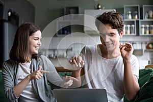 Millennial couple having fun listening to music online on laptop