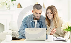 Millennial couple managing expenses with laptop and making notes photo