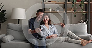 Millennial couple relax on couch with smart phone