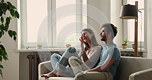 Millennial couple relaxing on cozy sofa discussing room remodelling