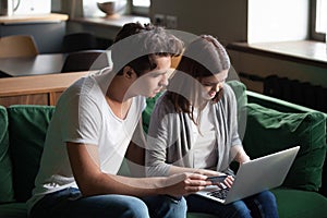 Millennial couple shopping online paying with credit card on lap