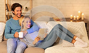 Millennial Couple Using Tablet Watching Movie Relaxing At Home