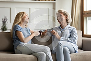 Millennial daughter drinking tea with older mom during pleasant conversation