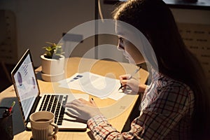 Millennial female employer typing on laptop and signing on docum