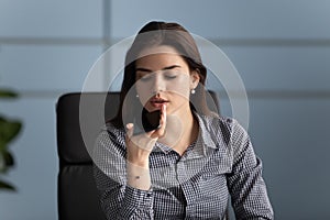 Millennial female worker holding smartphone recording voice message