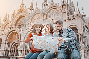 Millennial friends discuss a travel plan with a sightseeing map of Italy`s attractions. On San Marco square in