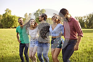 Millennial friends enjoying their time outdoors. Cheerful girls and guys spending summer day in countryside