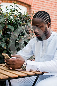 Millennial generation african american man typing sms outdoor 5g internet concept. High speed internet on phone and