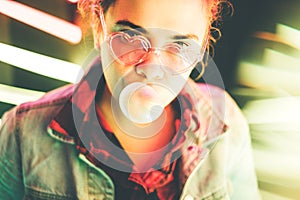 Millennial girl blowing bubble gum illuminated neon light