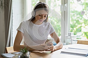 Millennial girl in earphones using smartphone gadget