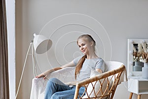 Millennial girl relaxing at home on cozy chair, enjoying free time