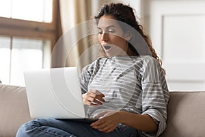 Millennial girl shocked reading news on laptop