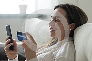 Millennial girl shopping on cellphone using credit card photo