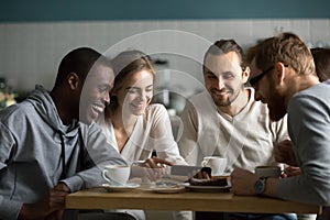 Millennial girl showing funny mobile video to friends in cafe