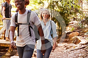 Millennial group of happy friends walking together during a hike in a forest, close up